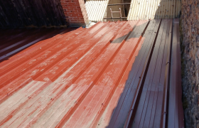Dépose d’une ancienne toiture en tuiles et pose d’une couverture en bac acier rouge.